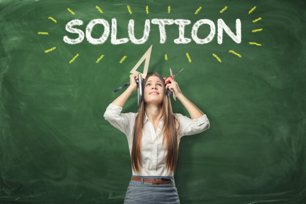 A young woman holding different office supplies in her hands and standing under the word 'olution'written above her head. Solving a problem. Never give up. A way out of the difficult situation.